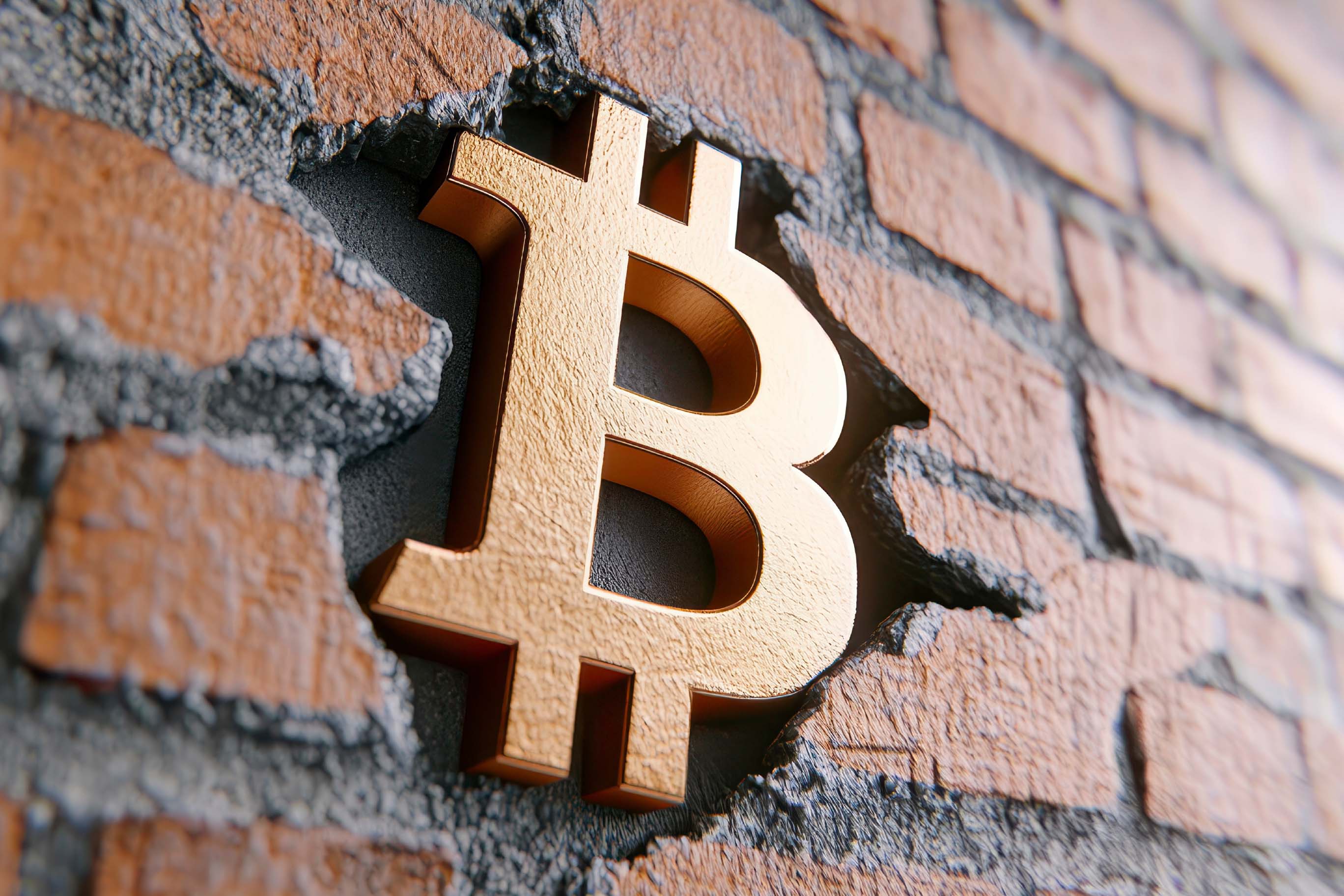 Close-up image showing a metallic gold Bitcoin logo firmly set into a broken or carved-out section of a textured brick wall.